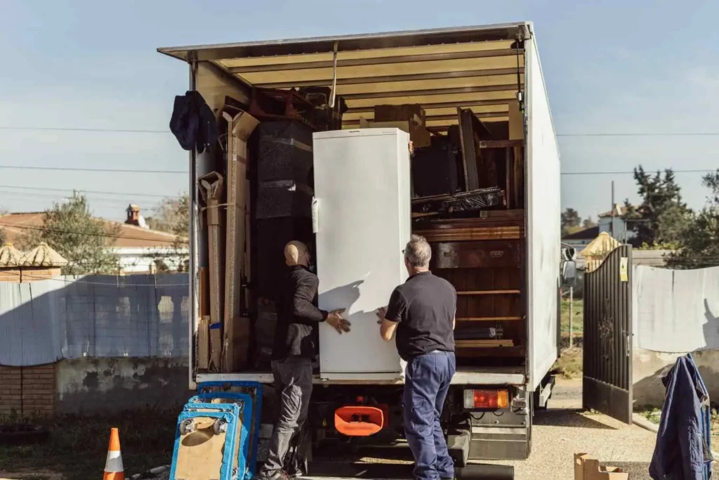 Licensed movers loading furniture onto a moving truck representing factors that affect moving costs